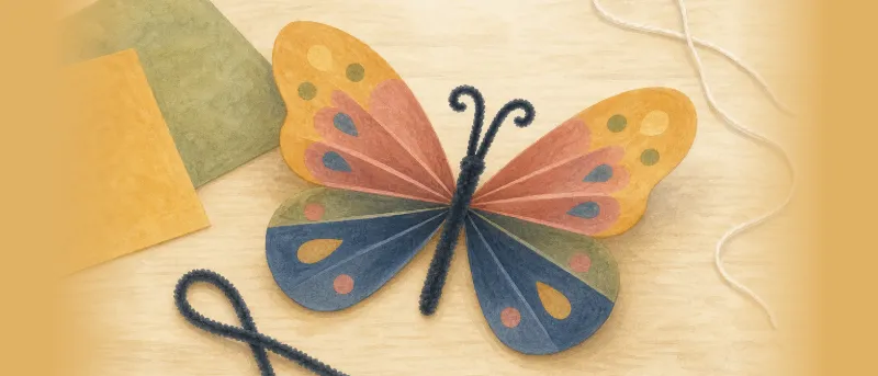 Fertiger bunter Papierschmetterling mit ausgebreiteten Flügeln auf hellem Holztisch – Schmetterling basteln mit Kindern als Titelbild